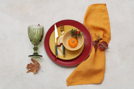 Beautiful table setting with fresh pumpkin, rose hip berries and autumn leaves on white backgroundの写真素材