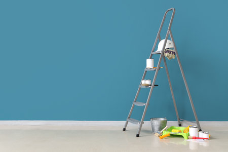 Stepladder with cans of paint and tools near blue wallの写真素材
