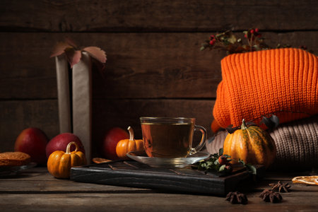 Composition with tray, cup of green tea and sweaters on wooden table near wallの写真素材