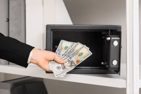 Businesswoman taking money from open safe in office, closeup