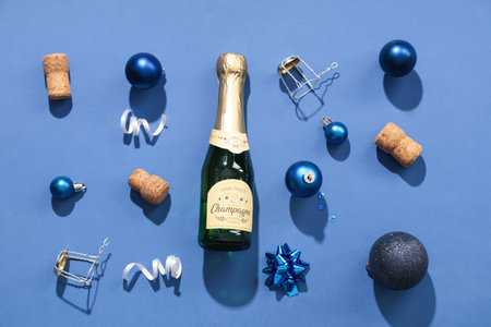 Bottle of champagne with corks and Christmas balls on blue backgroundの写真素材
