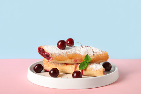 Plate with tasty cherry strudel and fresh berries on table near blue wall, closeupの写真素材