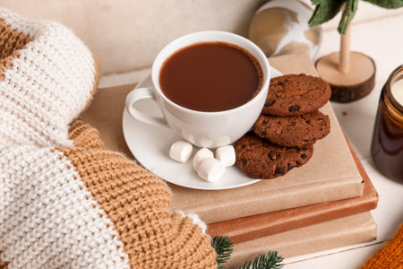 Beautiful composition with books, warm clothes, winter decor and cup of cocoa on white wooden backgroundの写真素材