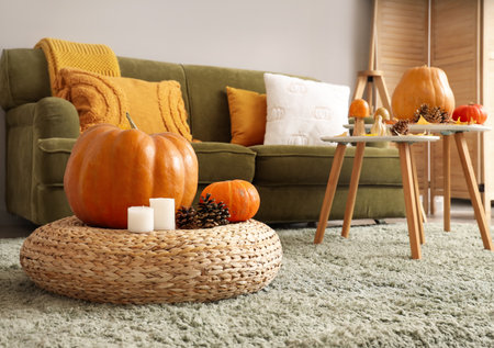 Cozy sofa, coffee table with autumn decor and pouf in interior of living room. Closeupの写真素材