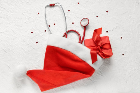 Stethoscope with Christmas hat and gift box on light backgroundの写真素材