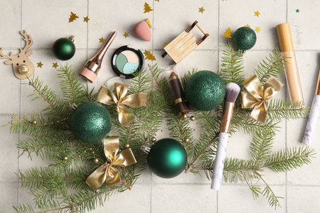 Different makeup products with Christmas tree branches and decor on white tile backgroundの写真素材