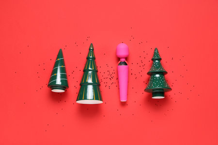 Composition with ceramic Christmas trees and vibrator on red backgroundの写真素材