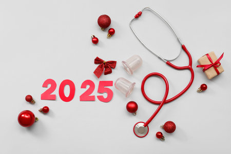 Composition with paper figure 2025, medical supplies and Christmas decorations on gray background
