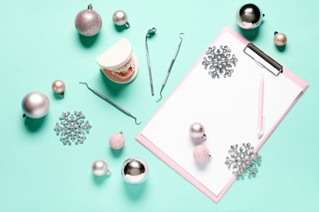Composition with blank clipboard, dentist's tools and Christmas decorations on color background