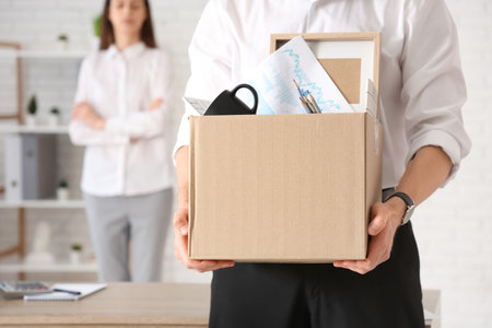 Fired young man with box of personal stuff and his colleague in office, closeupの写真素材