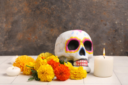 Painted human skull, marigold flowers and burning candles on light tile table. El Dia de Muertosの写真素材