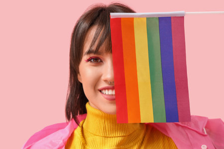 Beautiful young woman with LGBT flag on pink backgroundの写真素材