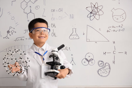 Cute little boy with molecular model and microscope in chemistry classroomの写真素材