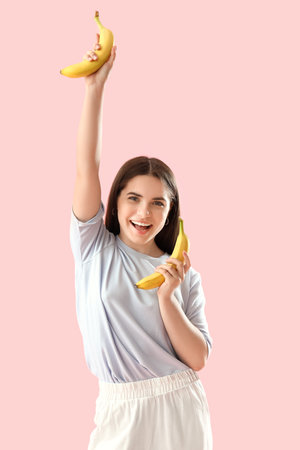 Happy young woman with bananas on pink backgroundの写真素材