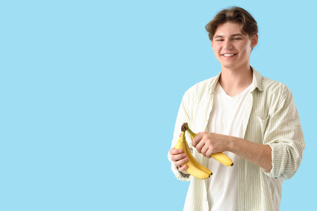 Young man with bananas on blue backgroundの写真素材