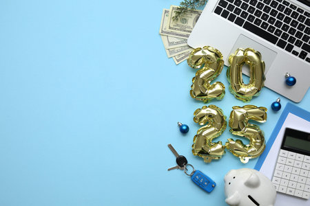 Figure 2025 with car keys, piggy bank, laptop and Christmas balls on blue background