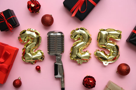 Figure 2025 with microphone, gifts and Christmas balls on pink background