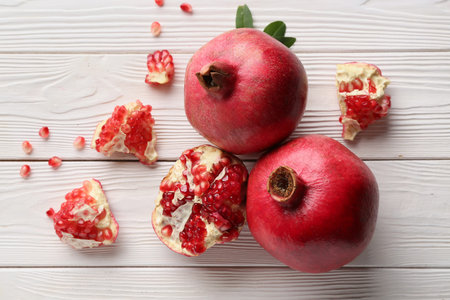 Fresh ripe pomegranates with seeds on white wooden backgroundの写真素材