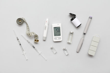 Glucometer with lancet pens, insulin and tape measure on light background. Diabetes conceptの写真素材