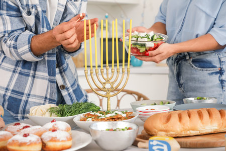 Happy family lighting candles on served dining table in festive kitchen. Hanukkah celebrationの写真素材
