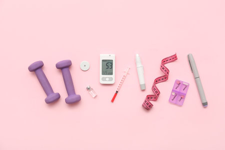Glucometer with lancet pens, glucose sensor and dumbbells on pink background. Diabetes conceptの写真素材