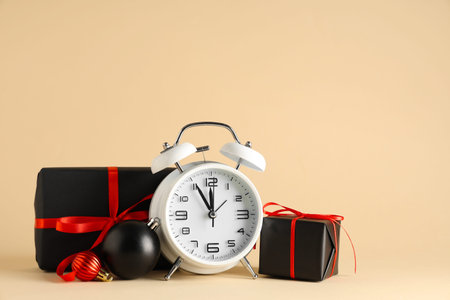 Alarm clock, gift boxes and Christmas balls on beige background