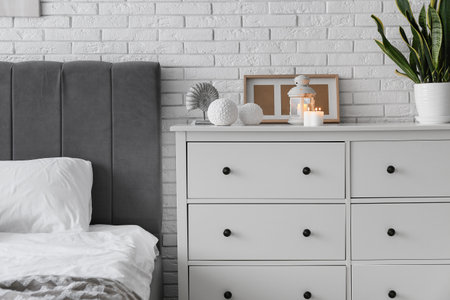 Burning candles on chest of drawers in bedroomの写真素材