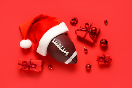 Composition with rugby ball, Santa hat, Christmas gifts and decorations on red backgroundの写真素材