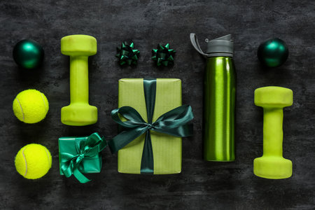 Composition with dumbbells, bottle of water, Christmas gifts and decorations on dark backgroundの写真素材