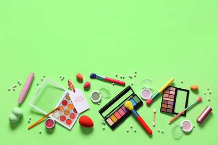 Composition with decorative cosmetics, makeup brushes and sale tag on green backgroundの写真素材