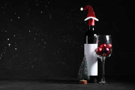 Bottle of wine and glass with Christmas baubles on black grunge backgroundの写真素材