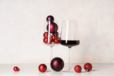 Wine glasses with Christmas baubles on white grunge backgroundの写真素材