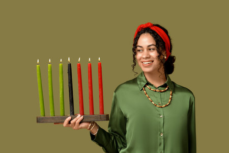 Young African-American woman with burning candles on green background. Kwanzaa celebrationの写真素材