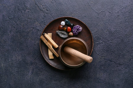 Set of chakra stones, palo santo and Tibetan singing bowl on dark backgroundの写真素材
