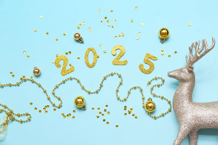 Figure 2025 made of paper, confetti, balls, beads and reindeer on blue background. New Year party. Top viewの写真素材