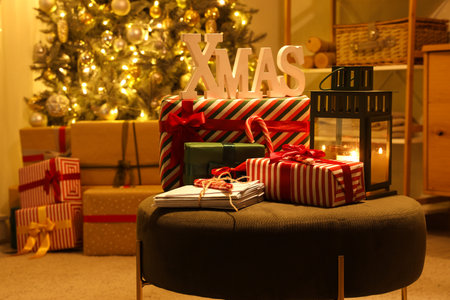 Christmas presents with letters and lantern on pouf in living room at night, closeupの写真素材