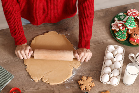 Young woman rolling out dough for Christmas gingerbread cookies on table, top viewの写真素材