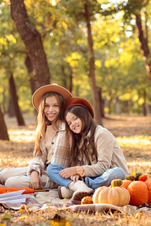Cute girls with pumpkins sitting on picnic in autumn parkの写真素材