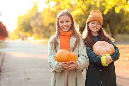 Cute girls with pumpkins in park on autumn dayの写真素材