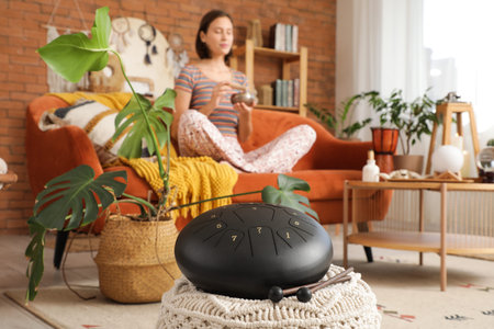 Glucophone on pouf against woman with Tibetan singing bowl at home, closeup