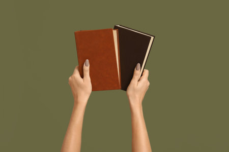 Hands holding books on color backgroundの写真素材