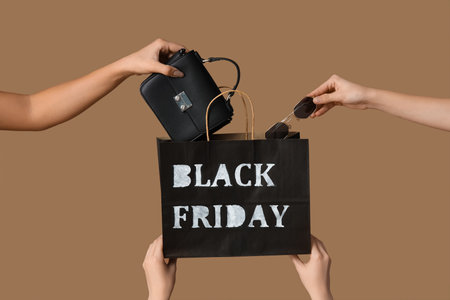 Hands with shopping bag and accessories on beige background. Black Friday saleの写真素材