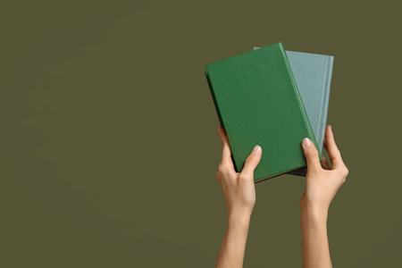 Hands holding books on color backgroundの写真素材
