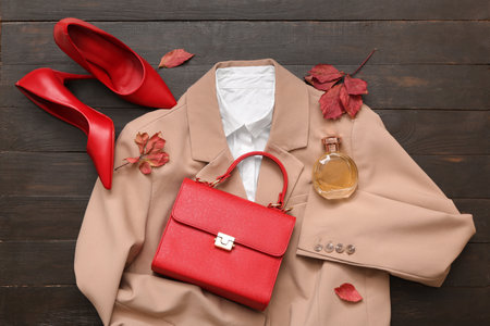 Stylish female bag with clothes, shoes and bottle of perfume on wooden backgroundの写真素材