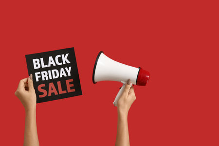 Hands holding megaphone and paper with text BLACK FRIDAY SALE on red backgroundの写真素材