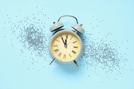 Alarm clock and confetti on blue background. Top view