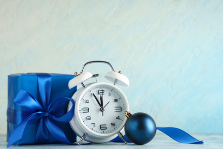 Alarm clock, gift box and Christmas ball on table against blue backgroundの写真素材