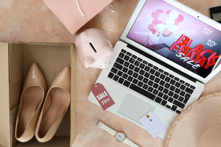 Laptop with Black Friday sale advertisement, piggy bank and female accessories on grunge backgroundの写真素材