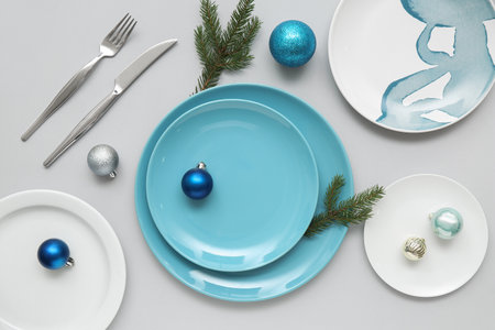 Beautiful table setting with Christmas balls and fir branches on gray backgroundの写真素材