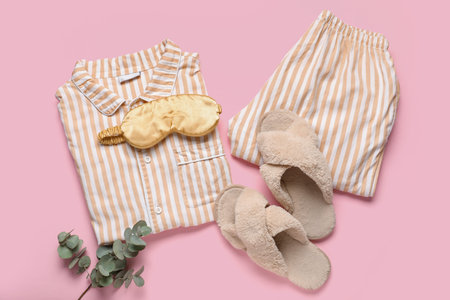 Striped pajamas with sleeping mask, slippers and eucalyptus on pink backgroundの写真素材
